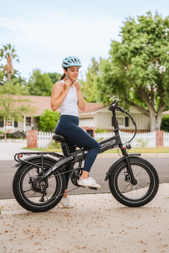 service-02 Caucasian woman with helmet adjusting straps while sitting on a bicycle in a suburban neighborhood.